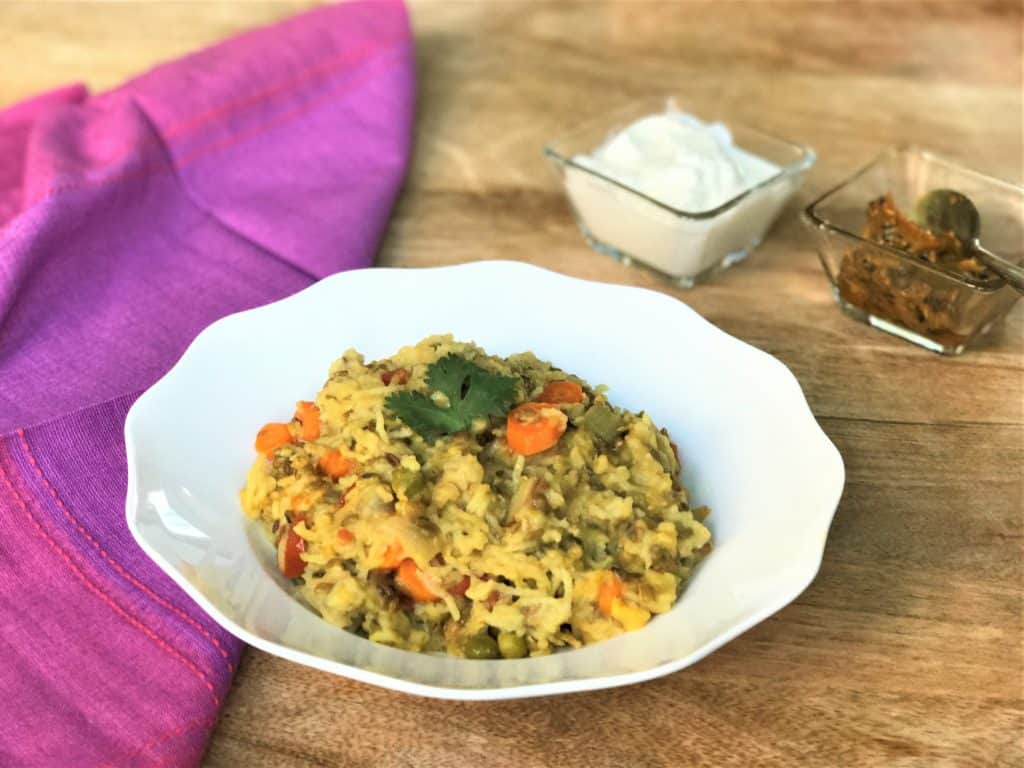 Lentil & Vegetable Khichdi or Masala Khichdi recipe made in Instant Pot or Pressure Cooker. A one-pot vegetarian comfort meal made with lentils, rice and vegetables along with simple spices and ghee | #khichdi #instantpot #pressurecooker #glutenfree Khichdi with vegetables in a white bowl along with pickle and yogurt.