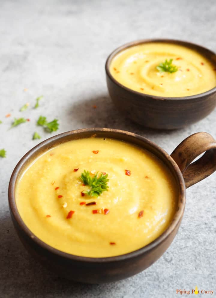 Turmeric Cauliflower Soup made in the instant pot in 2 serving bowls garnished with red chili flakes and parsley