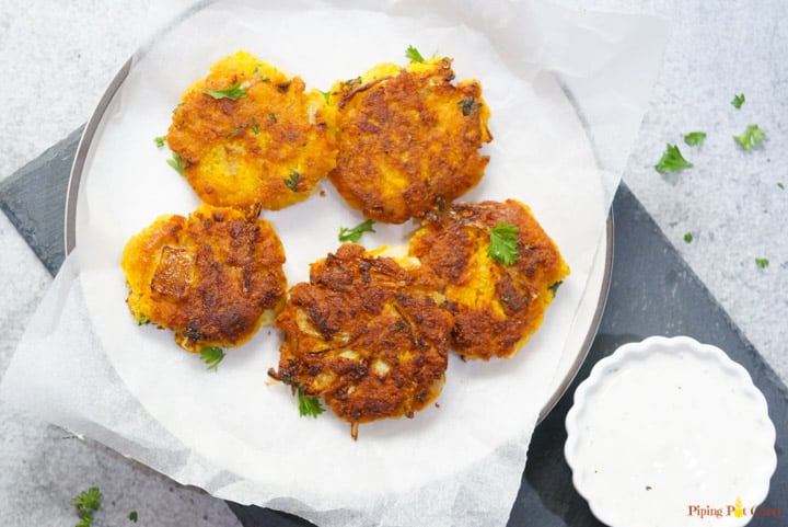 Vegan Chickpea Squash Fritters in a plate with yogurt dip on the side