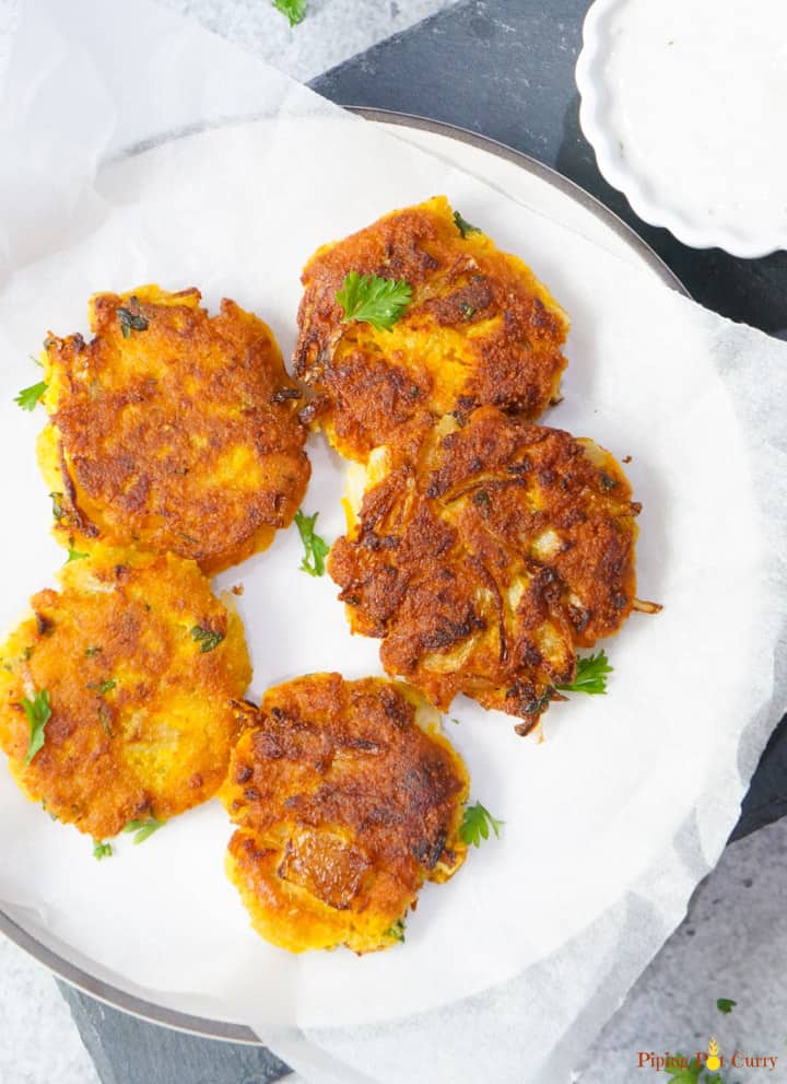 Try these super delicious and crunchy Chickpea Squash Fritters. These vegan & gluten free Chickpea Squash Fritters are so easy and take less than 30 minutes to make! Vegan Chickpea Squash Fritters in a plate with yogurt dip on the side