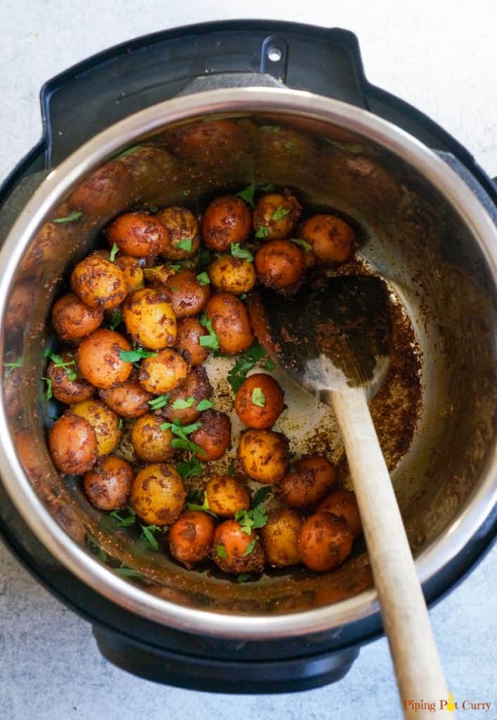 Spicy Bombay Potatoes or Masala Aloo, is baby potatoes cooked with aromatic spices. Perfect to serve as appetizer or a side dish, these delicious Bombay Potatoes take just 20 minutes to make in the Instant Pot | #babypotatoes #instantpot #potatoes #pressurecooker #bombaypotatoes #spicypotatoes | pipingpotcurry.com Instant Pot Spicy Baby Potatoes garnished with cilantro