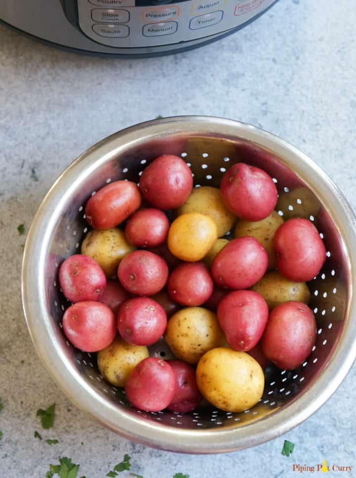 Super easy Instant Pot Steamed Baby Potatoes ready in less than 20 minutes. These baby potatoes are perfect to season and enjoy as a side with some rice or protein Baby Potatoes in a steamer basket in front of an Instant Pot