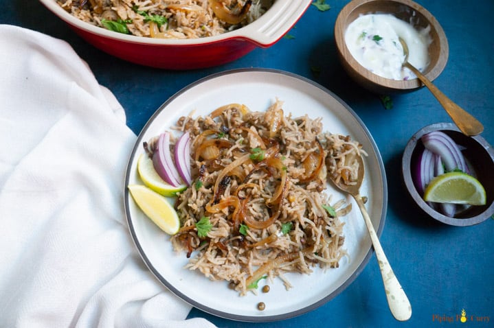 Instant Pot Lentils and Rice (Mujadara) in a white plate with yogurt, onions and lemon on the side.