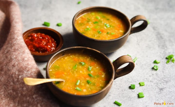 Easy & comforting Instant Pot Sweet Corn Soup. This lightly spiced Indo-chinese soup is perfect for the cold weather. This is a vegan & gluten free soup! Two bowls of Sweet Corn Soup made in the Instant Pot along with chili sauce on the side.