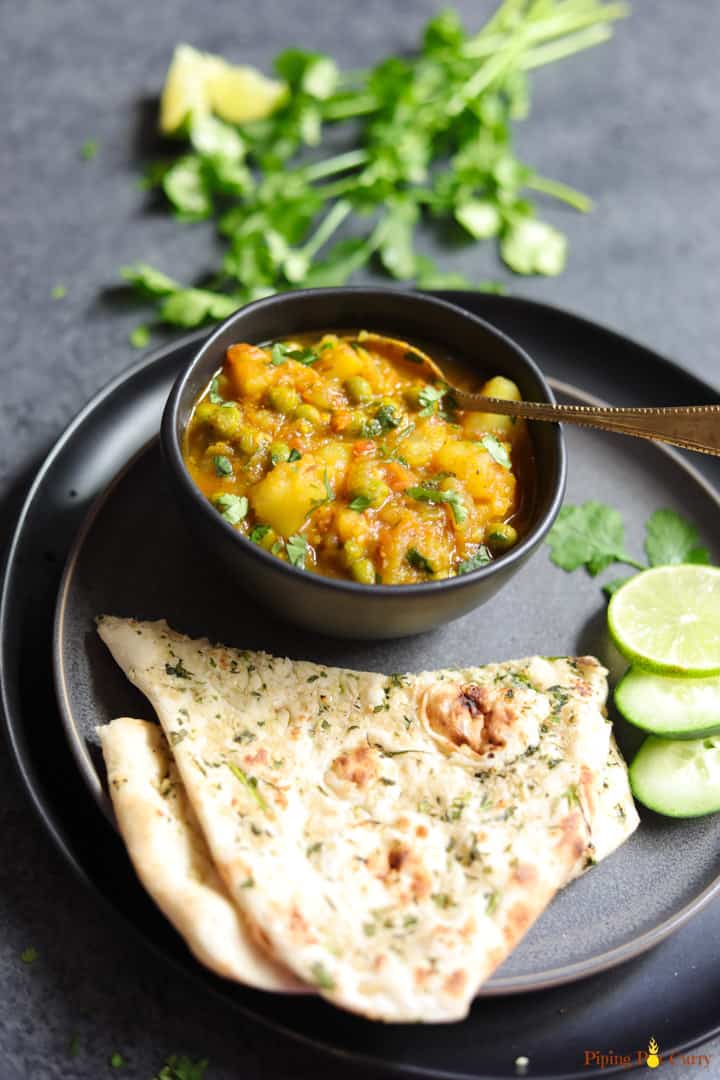 Aloo Matar is a quick and easy potatoes and peas curry, made in the Instant Pot or stovetop. This vegan and gluten free Aloo Matar Masala is perfect for a delicious warm weeknight dinner! #aloomatar #indian #curry #vegan #glutenfree #instantpot #pipingpotcurry | pipingpotcurry.com Aloo Matar made in instant pot served in a bowl, with naan bread on the side