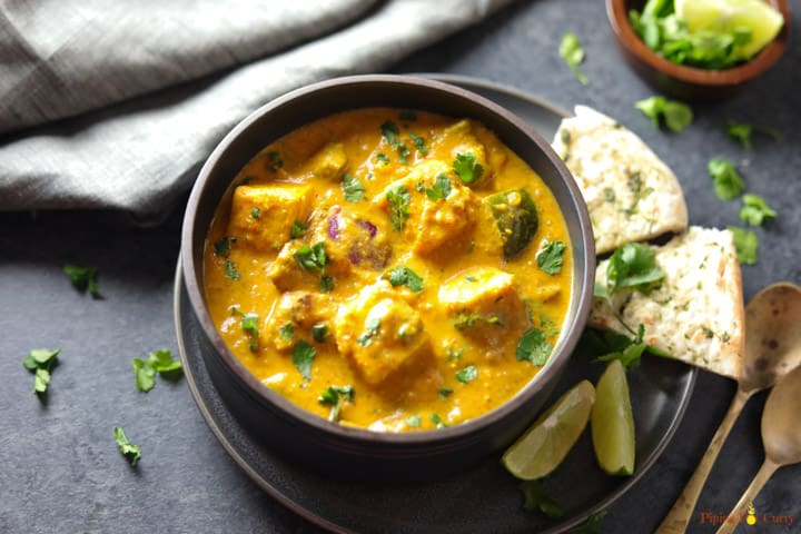 Paneer Tikka Masala is a flavorful and aromatic curry, made with marinated and grilled paneer cubes simmered in a rich onion tomato gravy along with warm spices. | #paneer #tikka #instantpot #pressurecooker #vegetarian #glutenfree #pipingpotcurry | pipingpotcurry.com Instant Pot Paneer Tikka Masala served in a bowl with some naan and limes on the side.