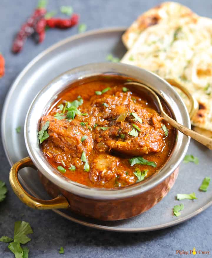 Chicken Vindaloo served in a bowl along with naan bread. 
