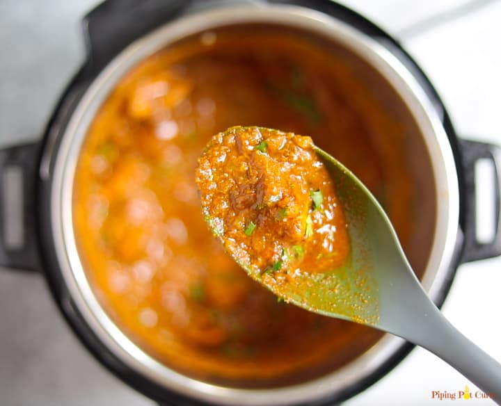 Chicken Vindaloo shown in a ladle over the instant pot ready to be served