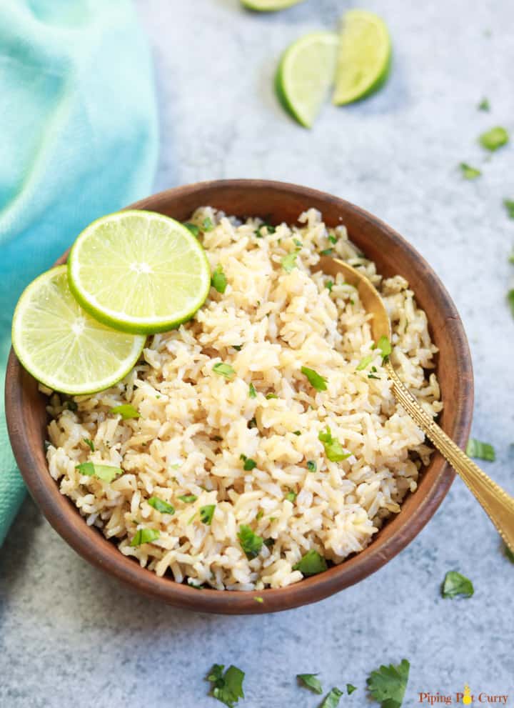 Instant Pot Cilantro Lime Brown Rice served in a brown bowl with lime slices and a spoon