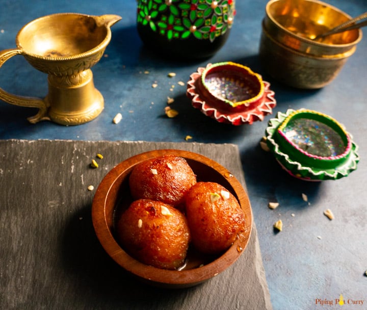 Gulab Jamun served in a small wooden bowl with a spoon.