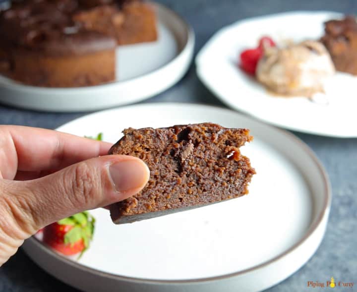 A closeup of a piece of brownie made in the instant pot, with the whole fudgy brownie cake in the back.