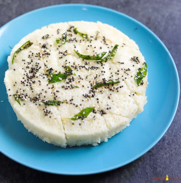 Rava Dhokla steamed in the instant pot served on a blue plate, topped with tempering