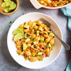 Shell Pasta topped with avocado and lime in a white bowl