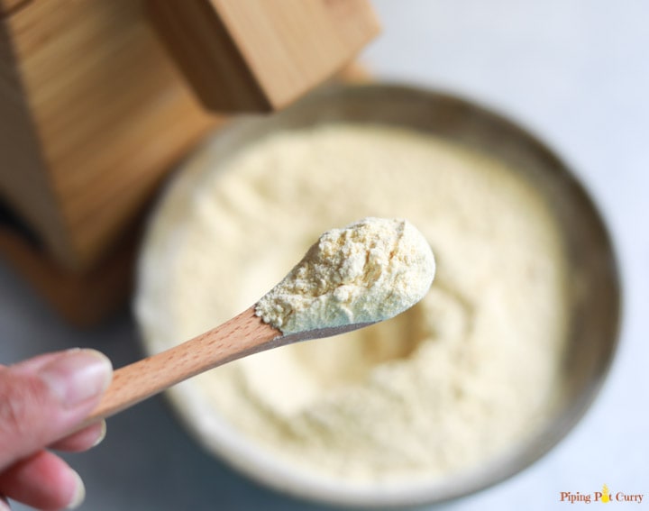 Finely ground chickpea flour in a spoon with Nutrimill in the back