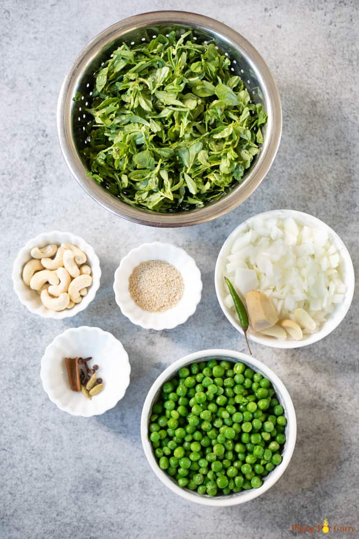 Ingredients such as fenugreek leaves, onions, peas and cashews in bowls.