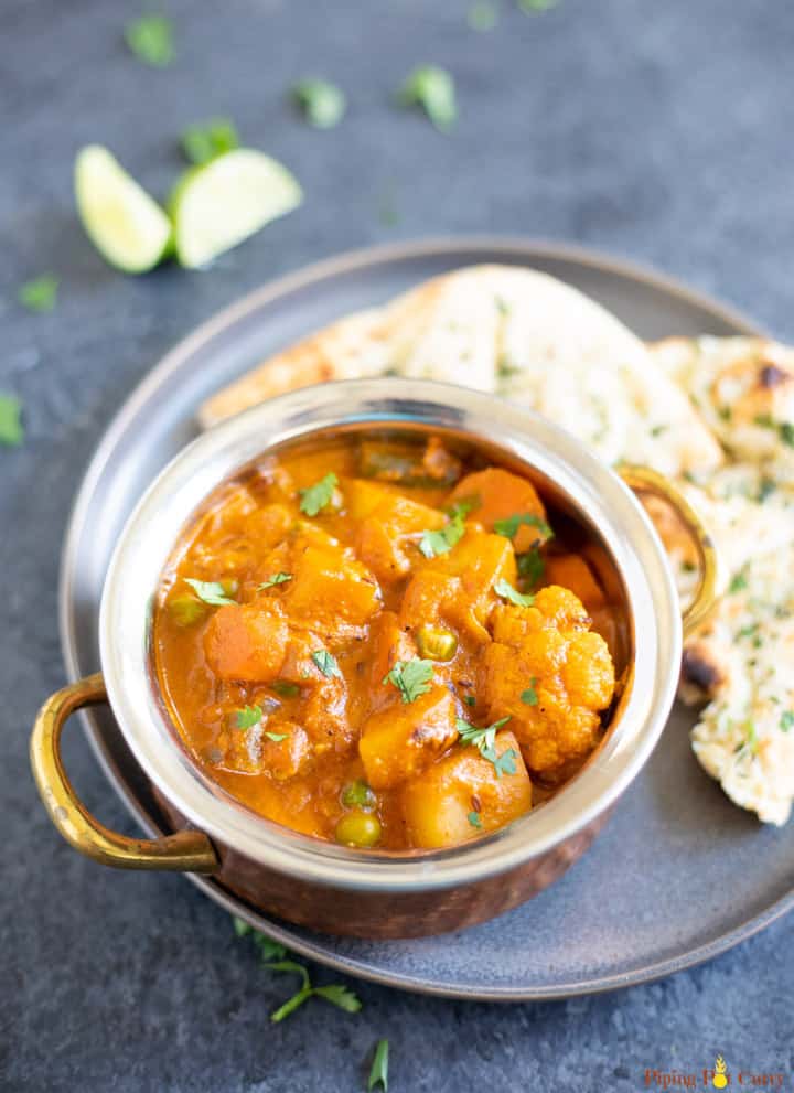 Vegetable Korma Curry in a bowl with naan on the side